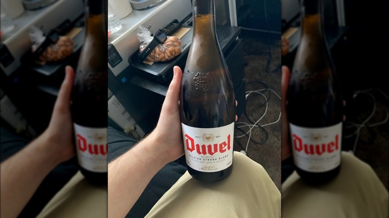 person holding Duvel beer bottle