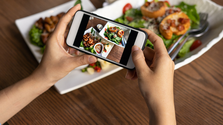 A woman taking a photo of food at an eatery