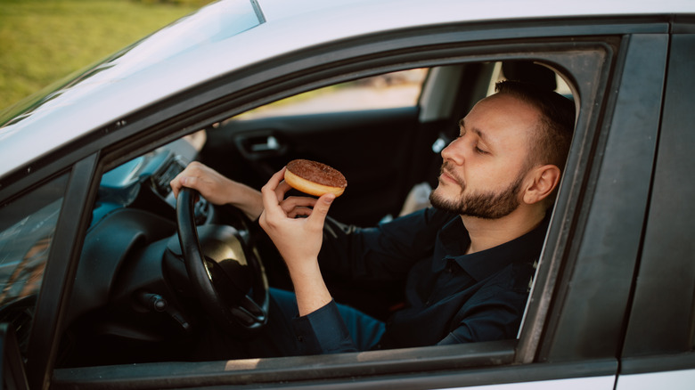 Man eating a donut in his car