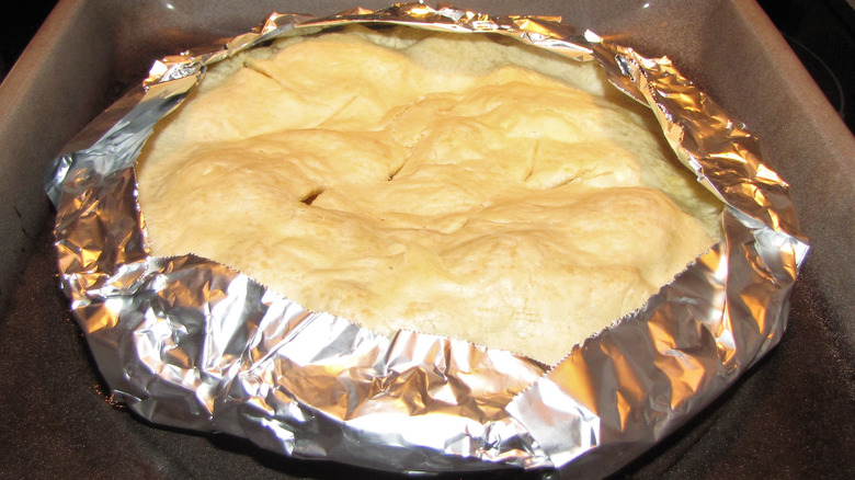 A homemade pie with aluminum foil around the edges