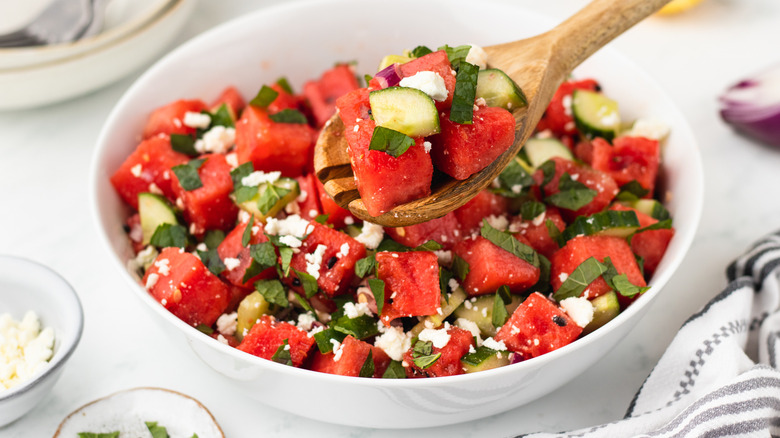 spooning watermelon salad from bowl