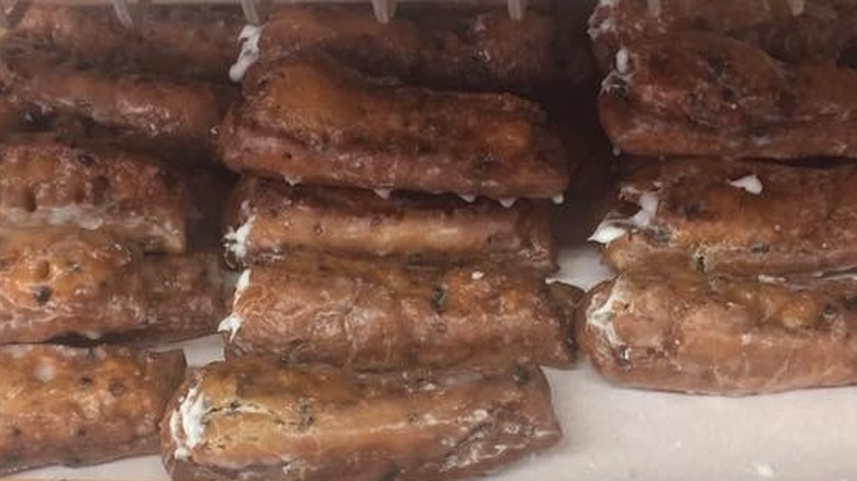 Dozens of cruller donuts on bakery shelf