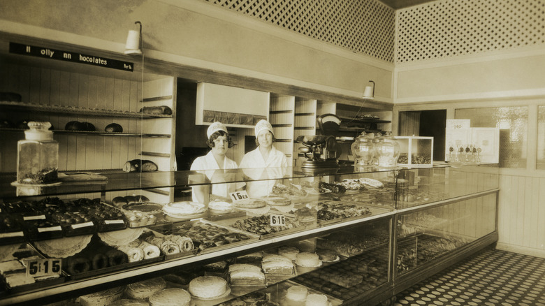 Black and white photo of two women standing behind counter of 1920s bakery