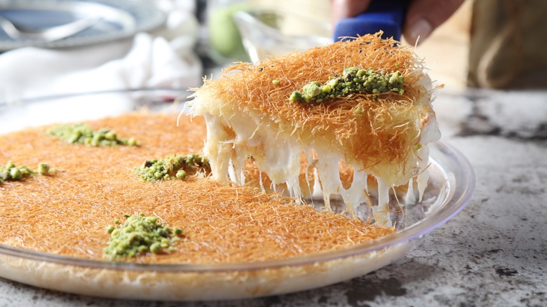 Person removing cheesy slice of knafeh