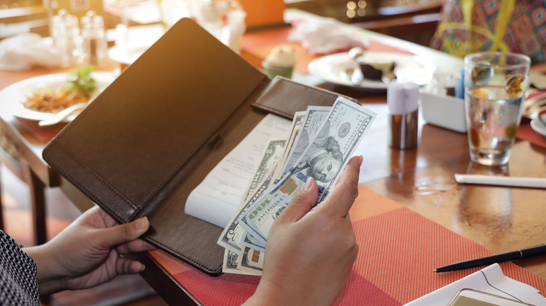Phone holding money and restaurant bill