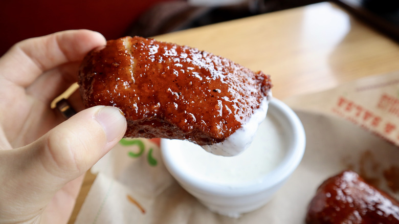 hand holding mozzarella stick dipped in ranch