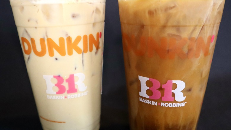 two Dunkin' drinks against black background