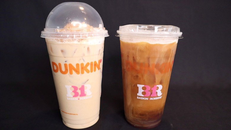 two Dunkin' drinks against black background