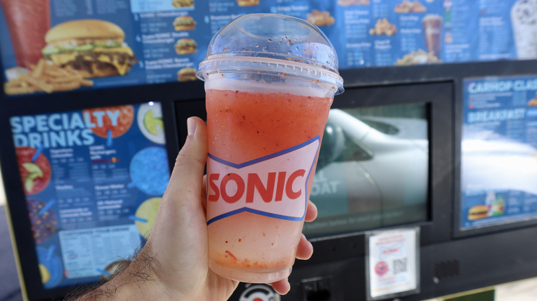 hand holding Sonic drink near menu sign