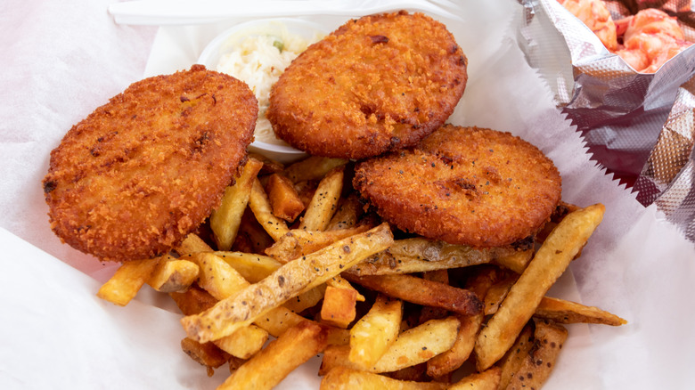 closeup of fried clam cakes with French fries on wax paper