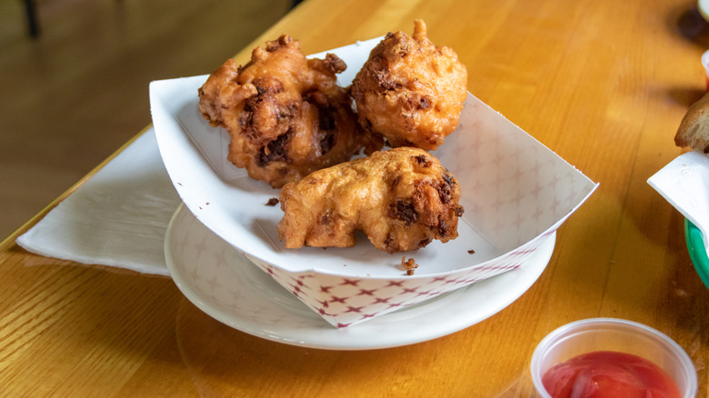 fried clam cakes in paper basket on table