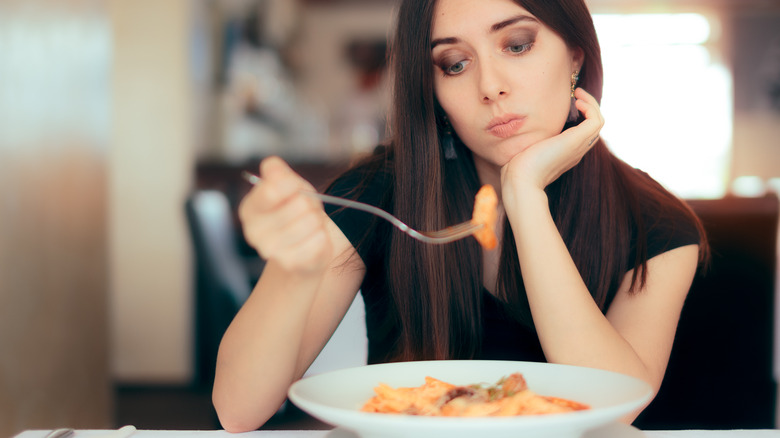 woman picking at pasta