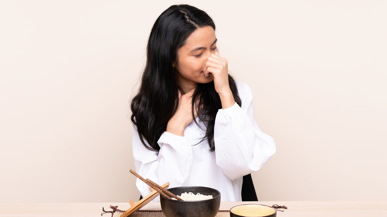 Woman plugging nose at bad rice