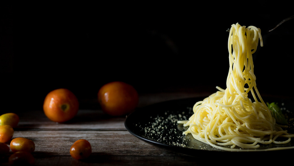 spaghetti and tomatoes being flipped in a pan 