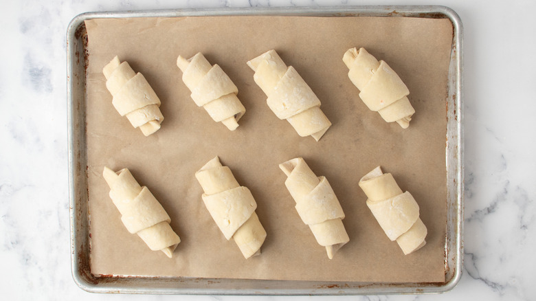 Rolled croissant dough on baking sheet