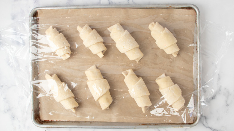 Croissants on baking sheet wrapped with plastic