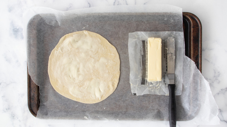 Butter spread on flattened dough disk