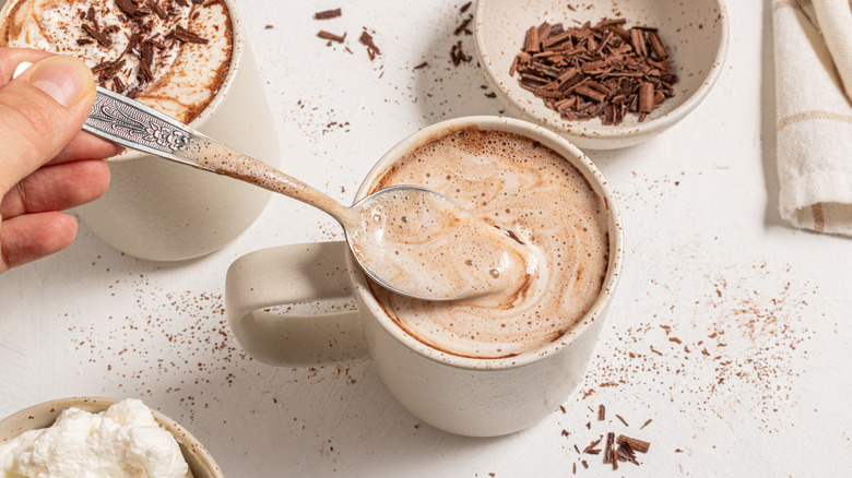 Scooping the foamy top off a cup with hot chocolate