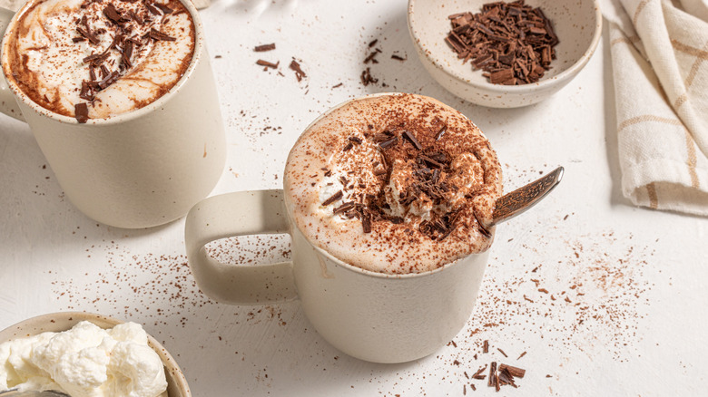 Two cups with espresso hot chocolate topped with whipped cream and shaved chocolate