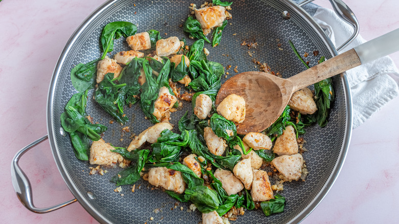 cooking chicken and spinach in a pan