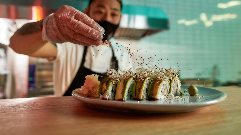 Person making sushi on a blue plate