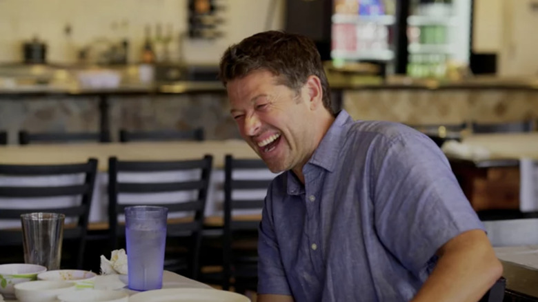 Misha Collins cracking up at a table