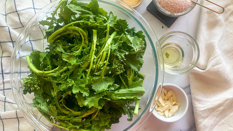 bowl of broccoli rabe next to salt, garlic and oil