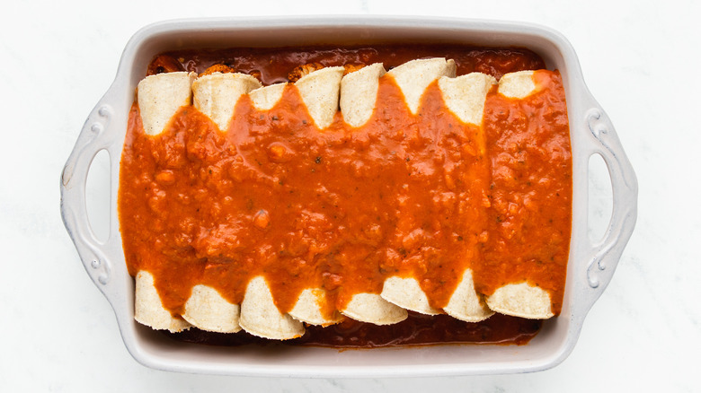 Tortillas and enchilada sauce in baking dish