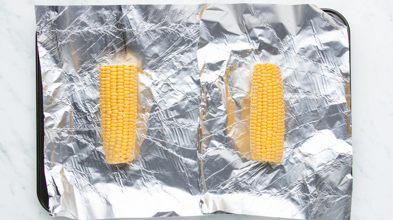 Ears of corn on foil-lined baking sheet