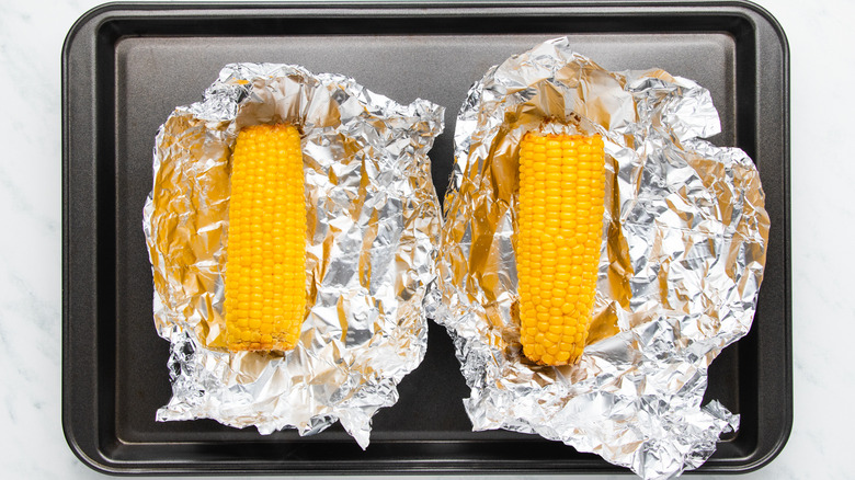 Roasted corn in foil on baking sheet