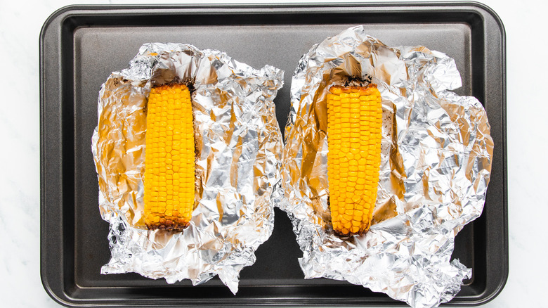 Roasted corn in foil on baking sheet