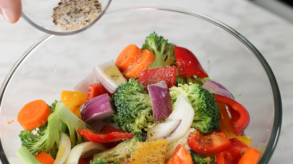 adding seasoning to roasted vegetables