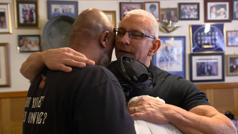 Robert Irvine hugging two restaurant owners