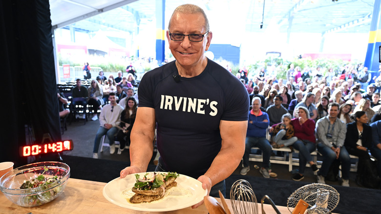 Robert Irvine holding fish dish at demonstration