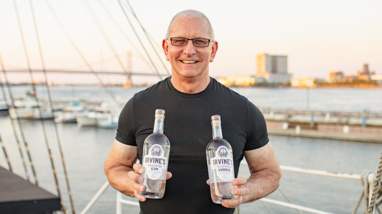 Robert Irvine holding liquor bottles on docks