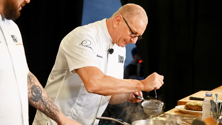 Robert Irvine cracking an egg into a pan