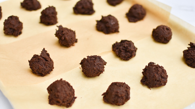 Uncooked cookie dough sitting on parchment paper on a baking sheet