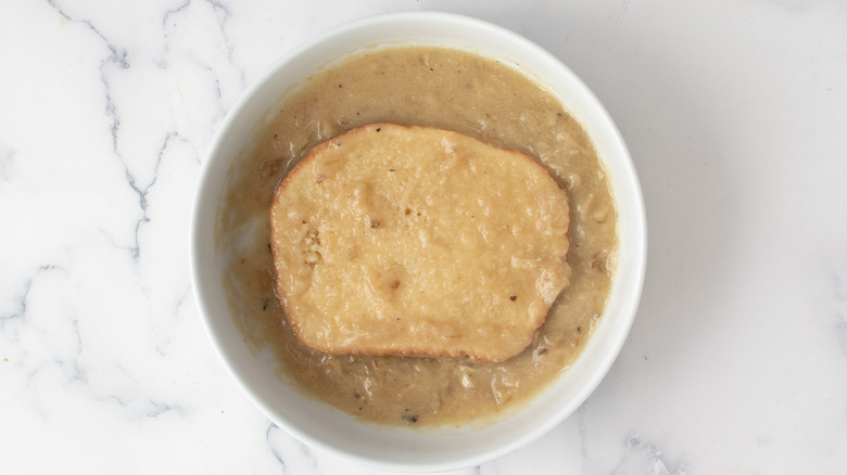 bread slice dipped in gravy in bowl