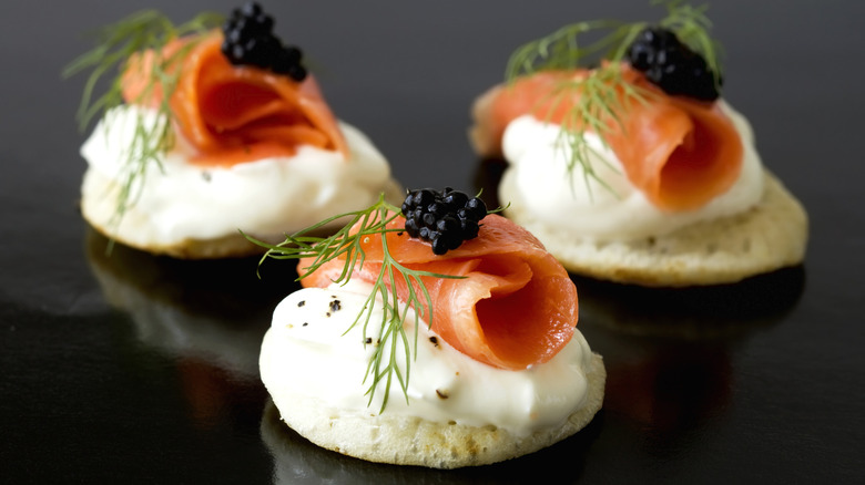 Small Russian blini topped with sour cream, smoked salmon, caviar, and dill