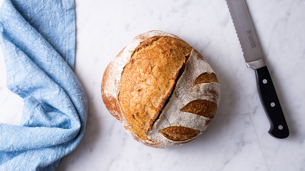 A loaf of sourdough bread next to a bread knife