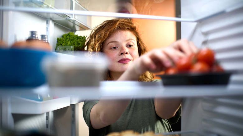 Woman reaching into fridge