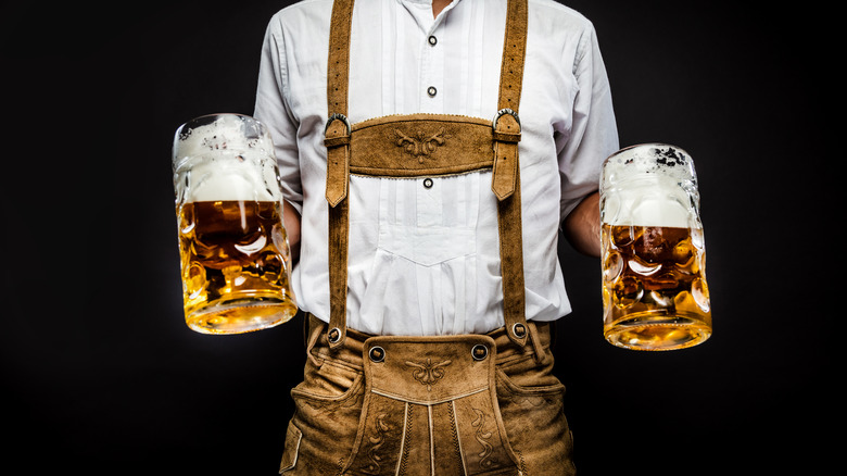 Man in lederhosen holding mugs of beer