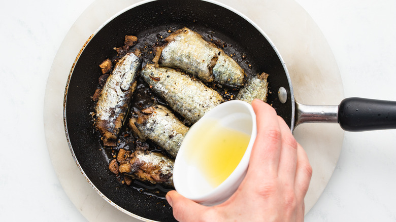 Lemon juice poured over sardines in pan