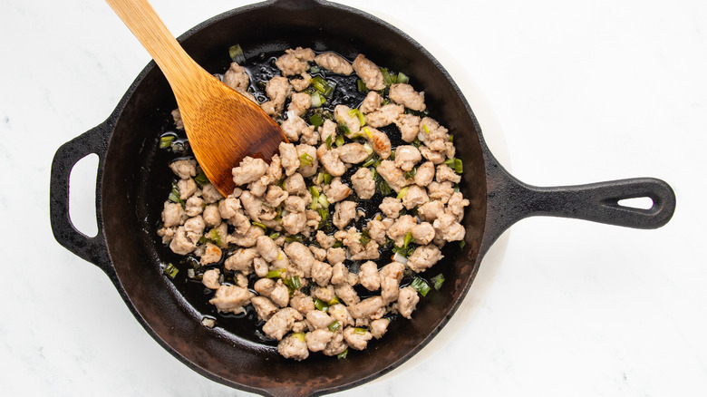 diced sausage and green onion frying in skillet