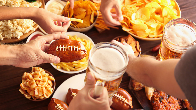 People with hands around Super Bowl snacks