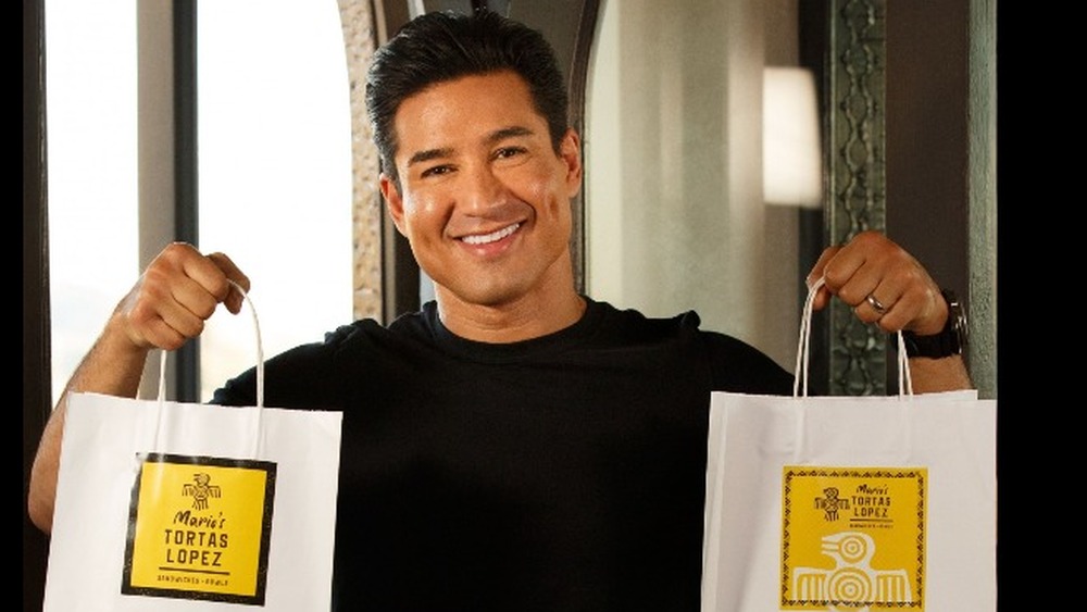 Mario Lopez holding up Tortas Lopez shopping bags