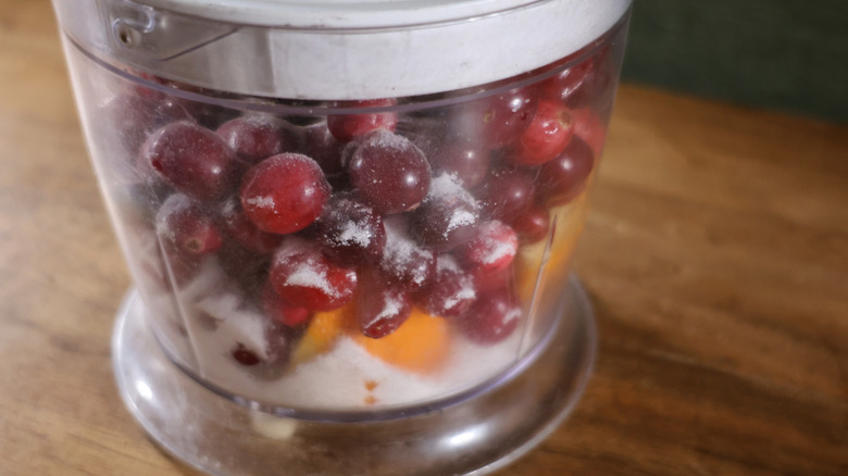 food processor full of cranberries, sugar, and orange pieces