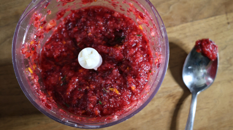 food processor full of cranberry relish with spoon next to it