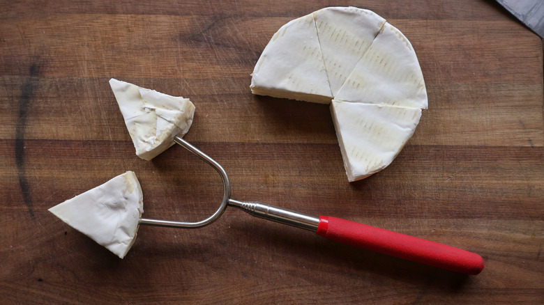 brie wheel sliced in sixths, with two pieces on metal skewer