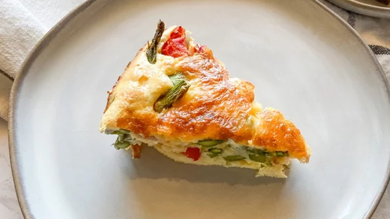 Slice of vegetable quiche on round plate.